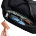 Bellroy Classic Duffel 45L - A close-up of a black duffel bag's interior, featuring a blue headset, a gadget, and a brown leather keychain.