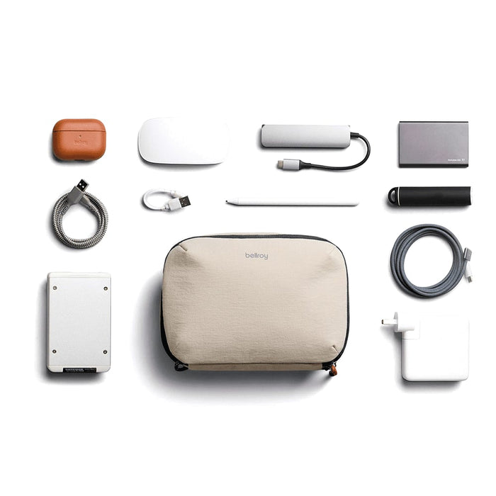 Bellroy Lite Tech Kit - A beige tech kit containing various accessories, including a power bank, cables, and a stylus, arranged neatly.