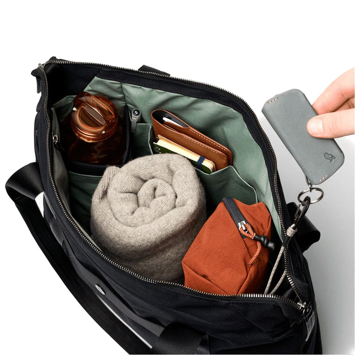 Bellroy Classic Tote - A black tote bag with a green interior, containing a drink bottle, a rolled blanket, a notebook, and a small brown pouch.