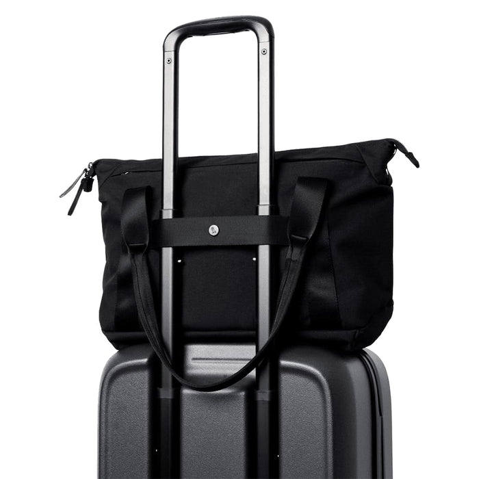 Bellroy Classic Tote - A black tote bag perched on top of a grey suitcase, featuring handles and a strap for carrying.