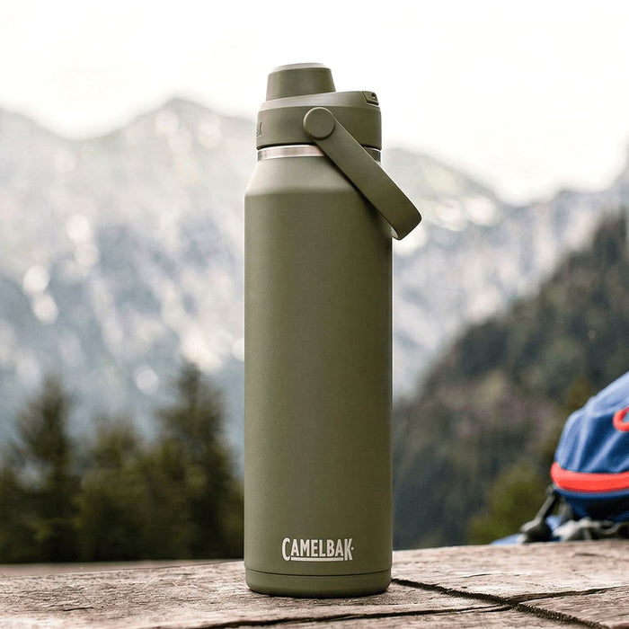 CamelBak - Thrive Chug VSS 1.0L - A drink bottle in olive green with a screw-top lid and a handle, featuring a logo. Set against a mountainous background.