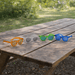 Summer Polarised Sunglasses - A set of four pairs of summer polarised sunglasses in orange, clear, green, and blue, displayed on a wooden picnic table.
