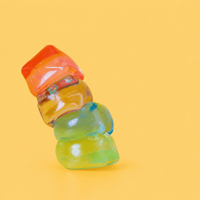 Jelly Cube Sensory Toy - A vibrant stack of jelly cube sensory toys in red, orange, yellow, and green against a bright yellow background.