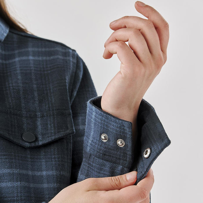Women's Highland Sherpa Lined Plaid Jacket - A close-up of a women's plaid jacket featuring a dark blue pattern and visible snap buttons on the cuffs.