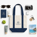Mini Canvas Tote - A mini canvas tote in navy and cream, surrounded by sunglasses, a camera, skincare products, and a notebook.