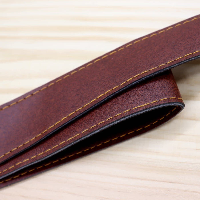 Saint-Rémy Cooler Basket - A brown leather strap with yellow stitching, laid on a wooden surface. The strap has a smooth finish and a sturdy appearance.