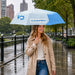 Anti-rebound Folding Umbrella - A light blue and white folding umbrella held by a woman wearing a beige trench coat, standing in the rain.