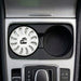 Air Freshener – Jasmine - A white air freshener sits in a car cup holder, featuring a circular design and a logo.
