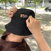 Bucket Hat with Card Pocket - A black bucket hat with a card pocket, held by a person in a casual setting.