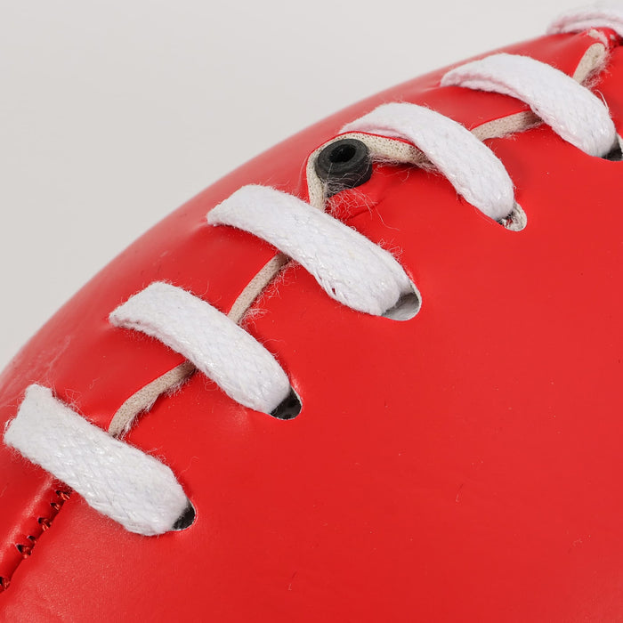 Mini Promotional Aussie Rules Ball - A red promotional Aussie Rules ball with white lacing and a smooth surface. It features a logo.