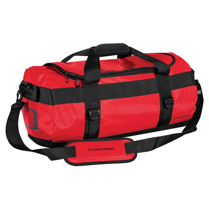 Stormtech Gear Bag Small - A red duffle bag with black straps and a handle, featuring a logo and adjustable shoulder strap.