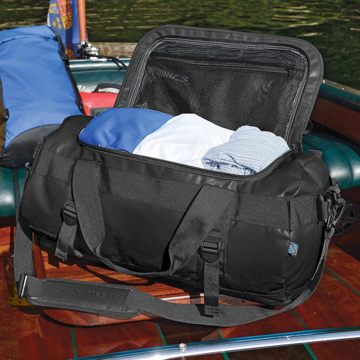 Stormtech Gear Bag Small - A black duffle bag with clothes inside, featuring a zippered top and a logo on the side.