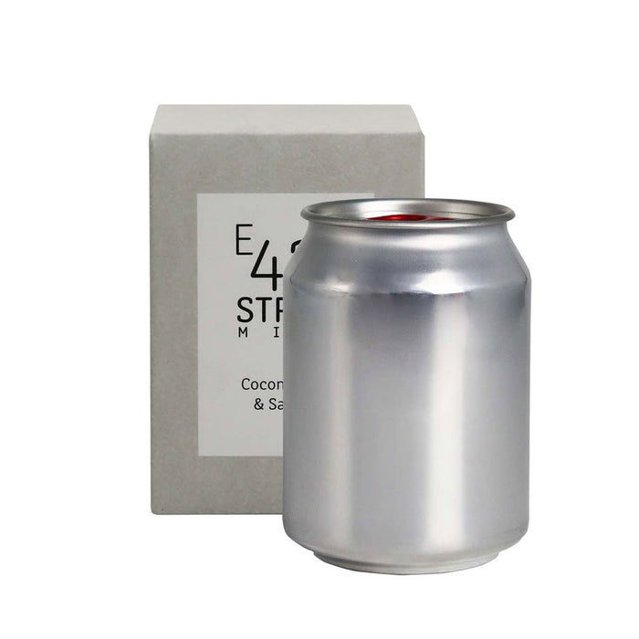 Mini East 42nd Street Can Candle - A silver can candle sits beside a square grey box, showcasing a sleek design and minimal branding.
