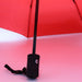 Poppins Umbrella - A red umbrella with a black handle and strap, featuring a logo on the handle.