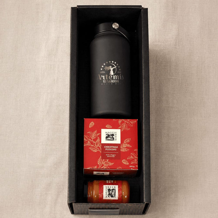 Festive Essentials Set - A black drink bottle, a red box of Christmas pudding, and a jar of sauce, all in a black hamper.