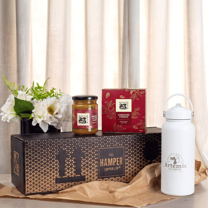 Festive Essentials Set - A white drink bottle, a jar of jam, a box of tea, and a floral arrangement in a gift box.
