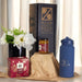 Festive Essentials Set - A blue drink bottle, a jar, a box, and a vase with flowers arranged on brown packaging.