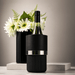 Trekk Insulated Adjustable Wine Cooler - A bottle cooler in black with a silver band, featuring a wine bottle and a vase of flowers in the background.