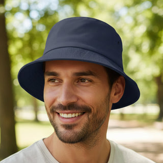 Long Beach Bucket Hat – Large - A navy blue bucket hat displayed on a smiling man, set against a park backdrop with trees. The hat has a logo.