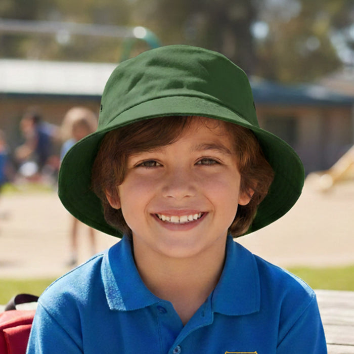 Long Beach Bucket Hat – Small - A green bucket hat on a smiling child, with a playground scene in the background. The hat has a logo.
