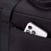 High Sierra Camille Duffel 31L - A black duffel bag features a zippered pocket with a smartphone partially visible inside.