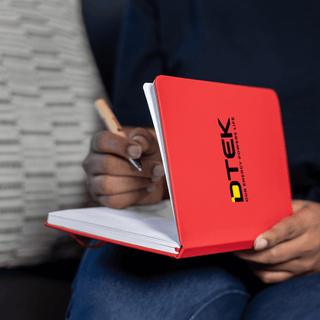 Space A5 Notebook - A red A5 notebook with a logo on the cover, held open with a hand writing inside.