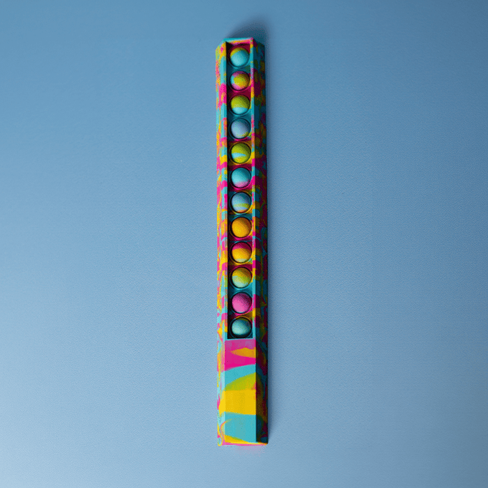 30cm Popper Ruler - A colourful 30cm popper ruler with a vibrant design and multiple popping buttons along its length, featuring a logo.