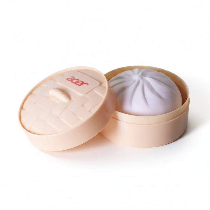 Squishy Bun - A squishy bun in a round, light peach container with a lid, featuring a soft purple bun inside.