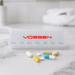 Doctor Pill Box - A transparent pill box with compartments for each day of the week, featuring various coloured pills beside it. It has a logo.
