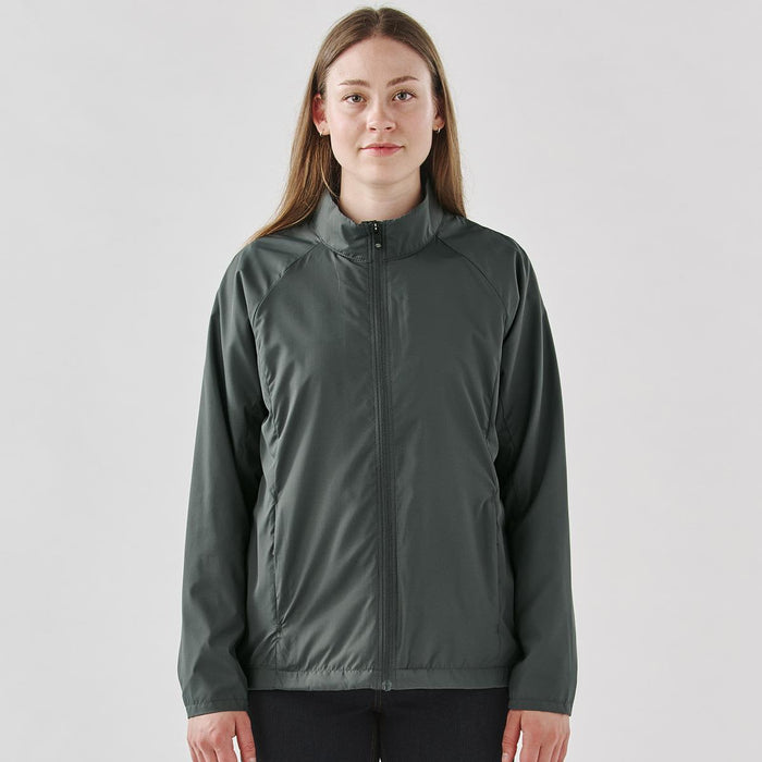 Women's Pacifica Full Zip Jacket - A woman wearing a dark grey full zip rain jacket with a stand collar and a logo on the chest.