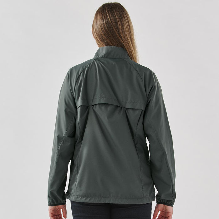 Women's Pacifica Full Zip Jacket - A woman wearing a dark grey full zip rain jacket viewed from the back, featuring a simple design and a logo.