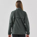 Women's Pacifica Full Zip Jacket - A woman wearing a dark grey full zip rain jacket viewed from the back, featuring a simple design and a logo.