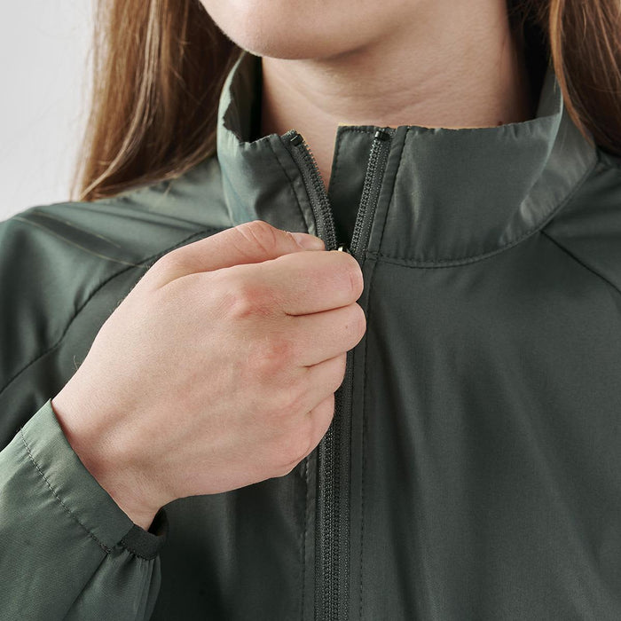 Women's Pacifica Full Zip Jacket - A woman's hand zips up a green Pacifica full zip jacket, featuring a high collar and a subtle logo.
