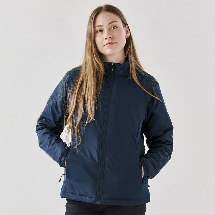 Women's Pacifica Thermal Jacket - A woman wearing a navy blue thermal jacket with a zippered front and side pockets, featuring a logo.
