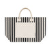 Hampton Tote Bag by The Line Edit. - A striped tote bag featuring black and cream colours, with a solid cream pocket and handles. It has a brand logo.