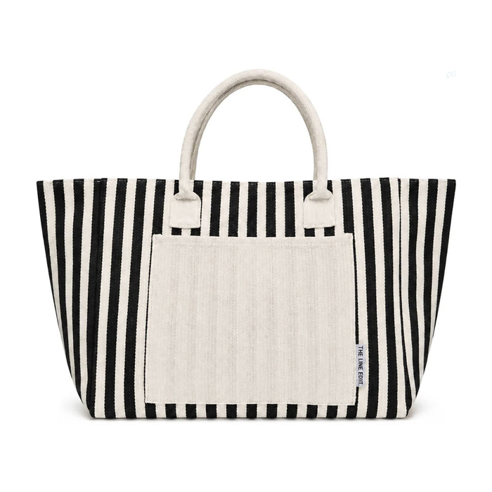 The Good Stuff Pack - A striped tote bag in black and white with a plain cream-coloured front pocket and handles. It has a logo.