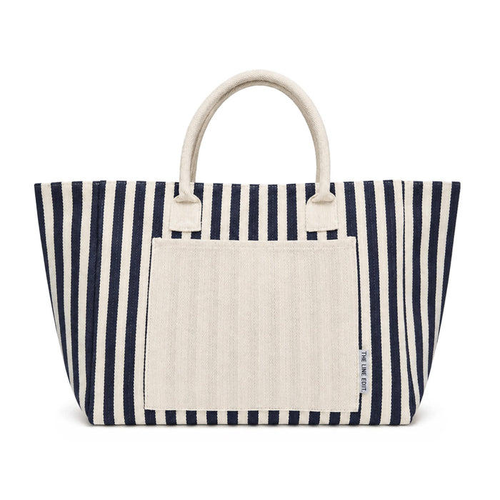 The Weekend Edit - A navy and cream striped tote bag with two sturdy handles and a front pocket. It features a branding logo.