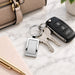Frame Keytag - A silver frame keytag attached to keys and a car remote, resting on a marble surface beside a pen and planner.
