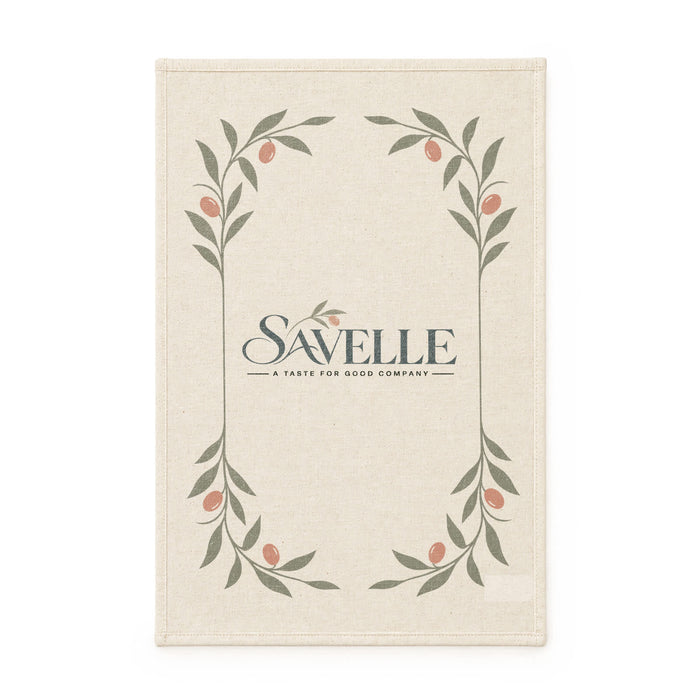 Haven Medium Cotton Tea Towel - A cream-coloured tea towel featuring a floral design with green leaves and small pink accents, with a logo at the centre.