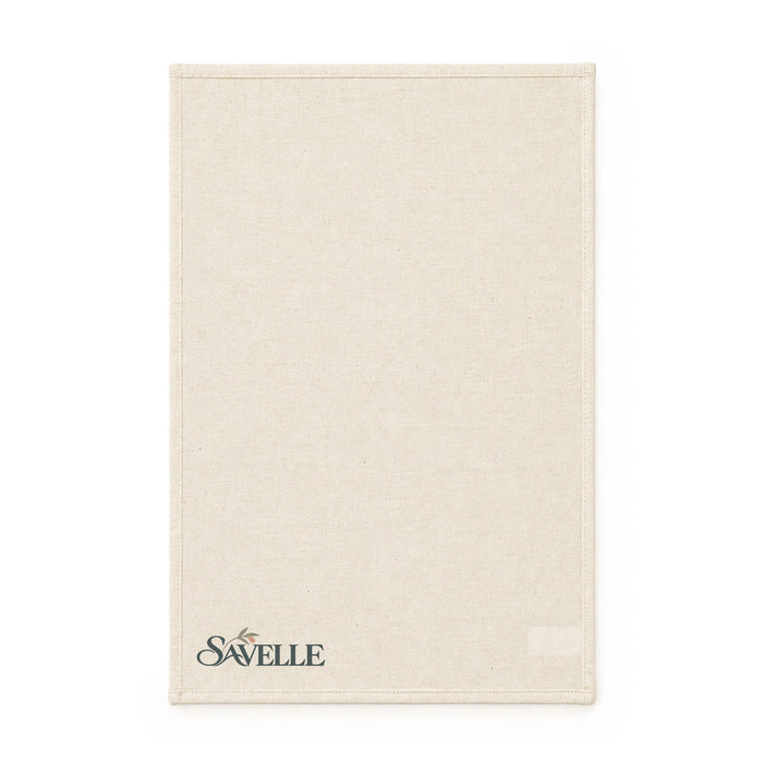 Haven Medium Cotton Tea Towel - A beige cotton tea towel featuring a logo at the bottom. The fabric has a textured appearance.