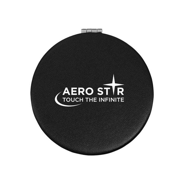 The Polished Traveller - A round black makeup mirror with a logo and a silver clasp. The mirror has a sleek, polished finish.