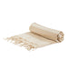 The Courtside Carry - A rolled beige and cream striped picnic blanket with fringed edges, featuring a simple design. It has a logo.