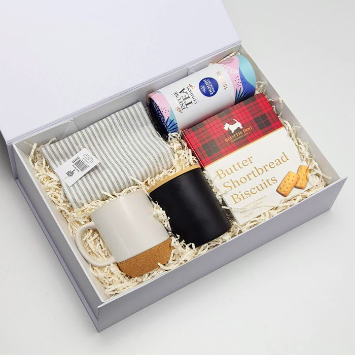 The Brew Ritual - A gift box containing a striped cloth, two coffee mugs (one white with a cork base, one black), and shortbread biscuits.