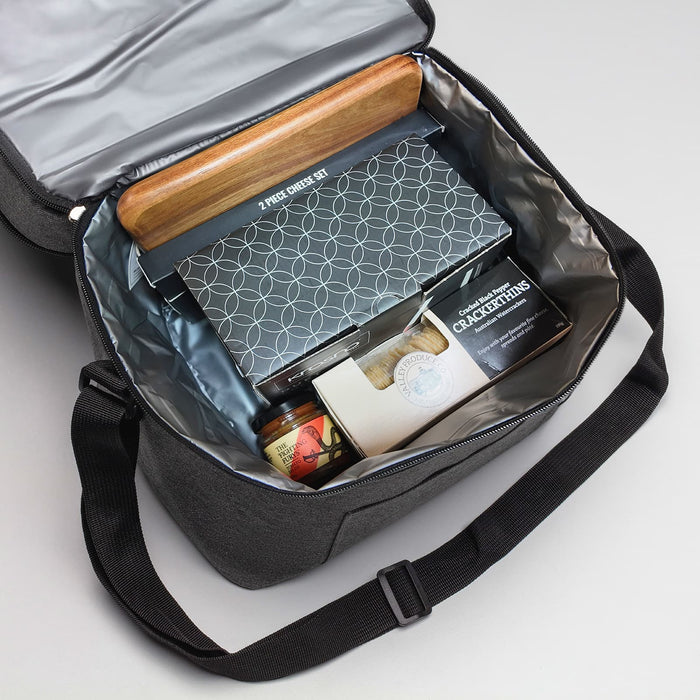 The Refined Graze - A cooler bag in grey containing a cheese set, jar, and assorted snacks. The interior is lined with silver material.