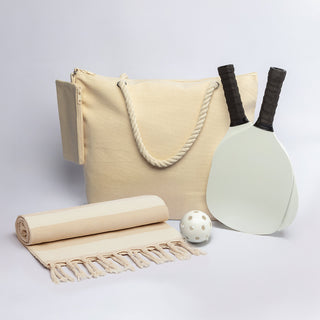 The Courtside Carry - A drink bottle, two paddles, a ball, a towel, and a cream tote bag, all featuring a simple design.