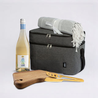 The Sunset Pour - A drink bottle, picnic blanket, wooden cutting board with knife, and a grey cooler bag. The drink bottle is white.