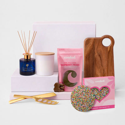 The Generous Host - A selection of gift items including a blue candle, a wooden board, raspberry frogs, and a sprinkles-covered cookie.