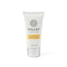 The Cosy Indulgence - A hand and nail cream tube in white and silver, featuring a floral logo and a yellow label.