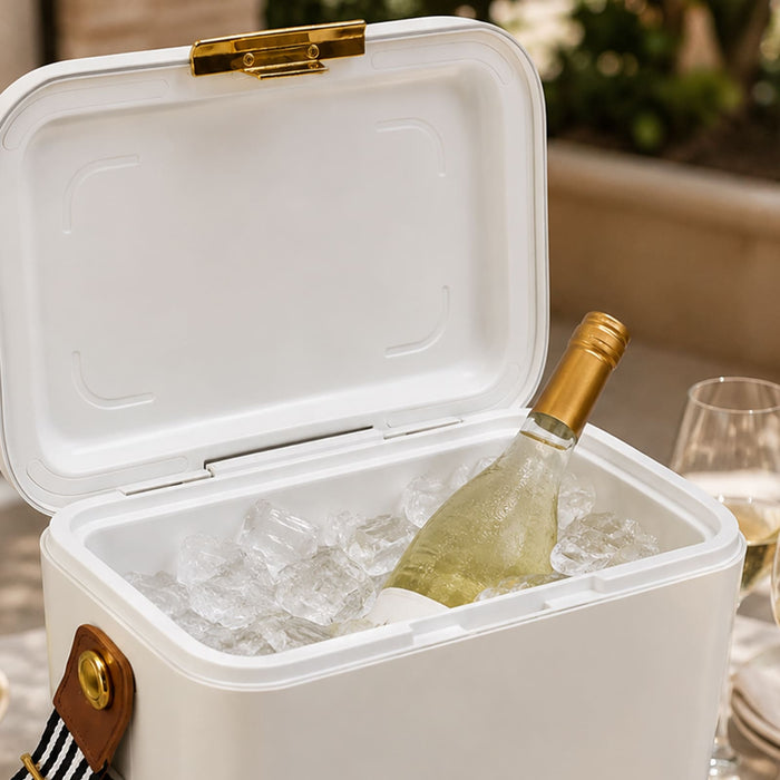 Pavilion Cooler by The Line Edit. - A white cooler filled with ice and a bottle of wine, featuring a gold latch and a striped handle.