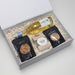 The Perfect Pairing - A drink bottle, black snack bags of pretzels and salted nuts, and a caramel fudge treat in a white gift box.
